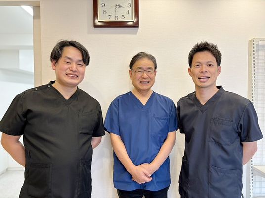 スタッフ3人の壁前  