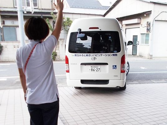 送迎車に手を振るスタッフイメージ  
