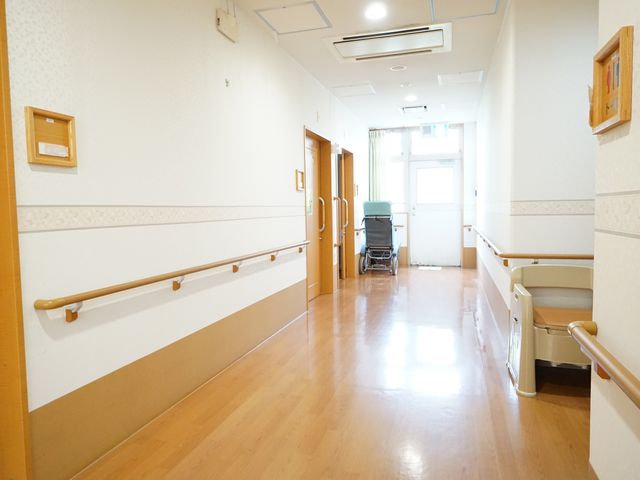 清潔な廊下の一角 廊下 明るく広々とした通路は、手すりが整っており、車椅子もスムーズに移動できる造りです。待機している車椅子もあり、安全に配慮された環境が整っています。