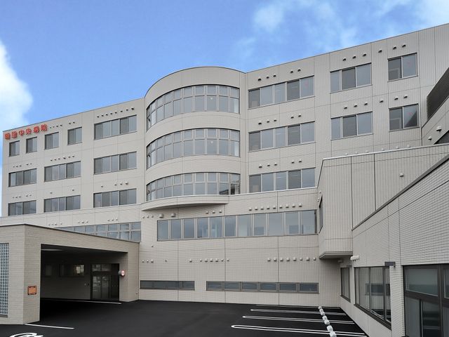 病院外観 外観   白い外壁と大きな窓が印象的な建物です。青空の下で、車の乗り入れもしやすそうな広い前面スペースが見えます。