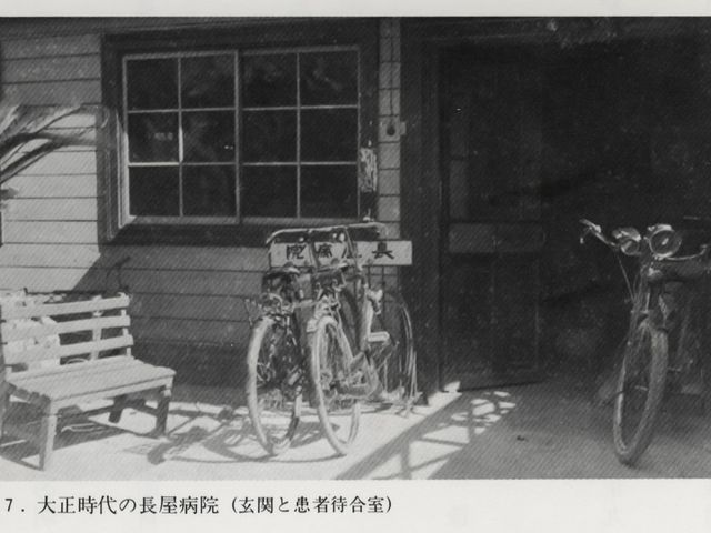 病院玄関前の自転車置き場 外観   木造の建物前に自転車が並び、ベンチも置かれています。玄関まわりの落ち着いた雰囲気が伝わります。