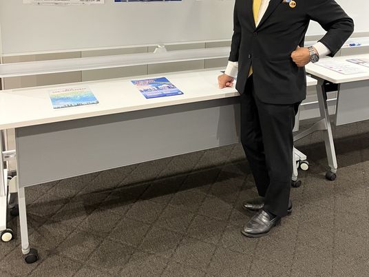 説明用テーブルの前に立つ男性  