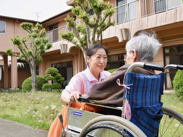 庭で交流する様子 庭 丁寧な介助を行うスタッフが、車椅子の方と談笑しています。温かみのある人間関係が魅力です。