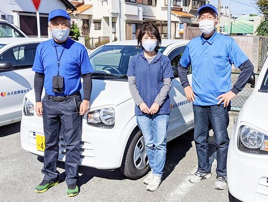 送迎車の前に立つ職員  
