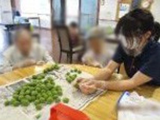 人々が作業する共有スペース ラウンジ 広々とした明るい空間で、入居者がスタッフと一緒にリラックスして活動を楽しんでいます。
