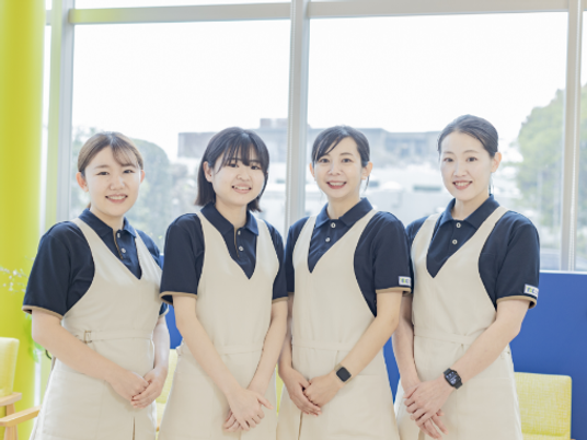 笑顔のスタッフ4人が並ぶラウンジ  