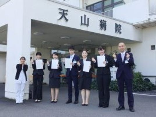 病院前で並ぶスタッフと看板外観  