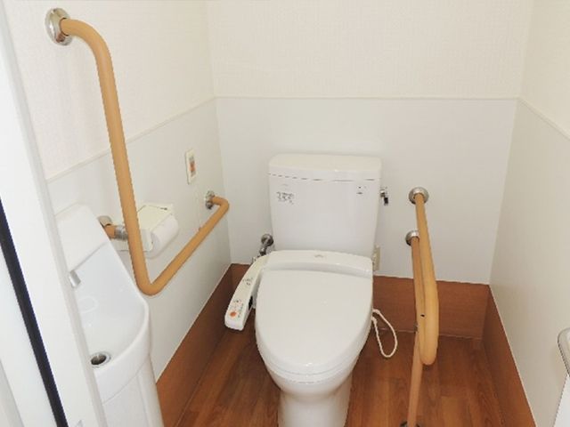 手すり付きトイレ トイレ   手すりが複数設置された、立ち座りを支えやすいトイレです。車椅子からの移乗にも配慮されたつくりがうかがえます。