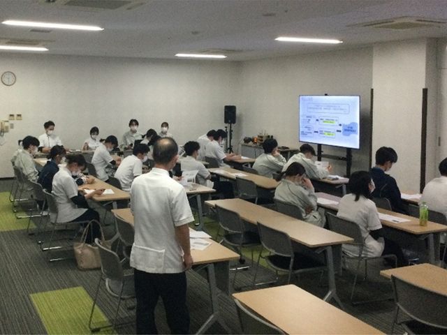 研修中の多目的室 多目的室   机と椅子を並べた広めの多目的室で、前方の画面を見ながら研修が行われています。スタッフの学びの場として使いやすい空間です。