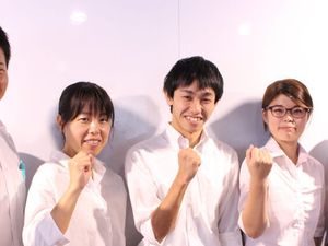 笑顔のスタッフたちが並ぶ室内  