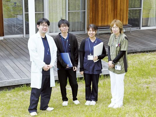 屋外に立つ職員と建物外観  