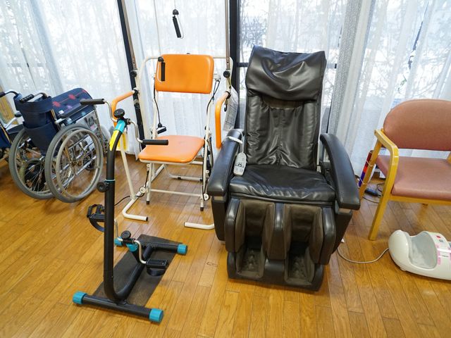 機能訓練機器と車いす 共有スペース 快適な環境のもと、日々の体力維持やリハビリに役立つ設備が整っています。利用者の健康サポートを考えた空間となっており、就業を検討される方には充実した職場です。