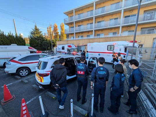 医療スタッフと車両が並ぶ外観  