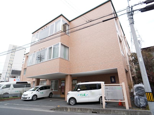 建物正面と駐車場 外観 ゆとりある駐車スペースが確保された建物外観です。明るく清潔感があり、気持ちよくお迎えする環境が整っています。