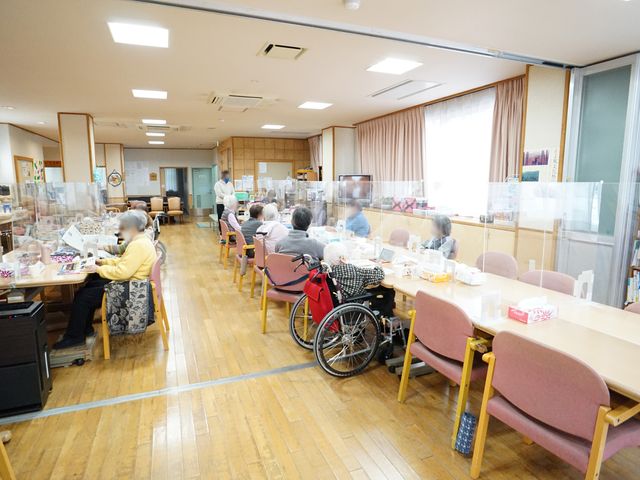 明るい共有スペース 共有スペース 座っている方々が交流を深める広々とした食堂です。椅子や車椅子でも安心して過ごせる明るく開放的な環境が整っています。