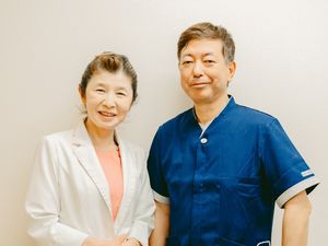 白衣の女性と職員の立ち姿