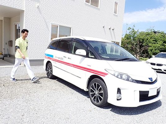 送迎車と歩く職員の外観  