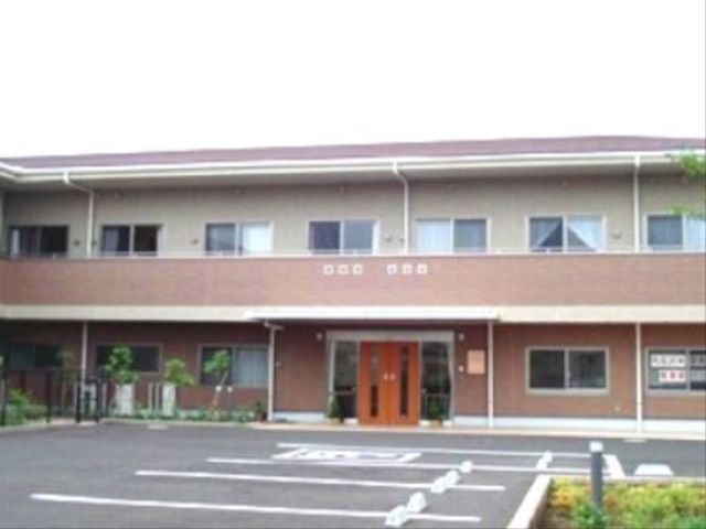明るい外観の建物エントランス 外観 エントランスが明るくて清潔感があり、訪れる方を暖かく迎える雰囲気です。駐車スペースも広々としており、来訪者の利便性も考慮されています。