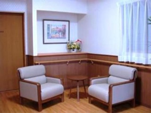 応接エリアの清潔な居室 エントランス ゆったりとした椅子が配置された居室の一角です。壁の装飾や窓からの自然光が心地よい空間を演出しています。