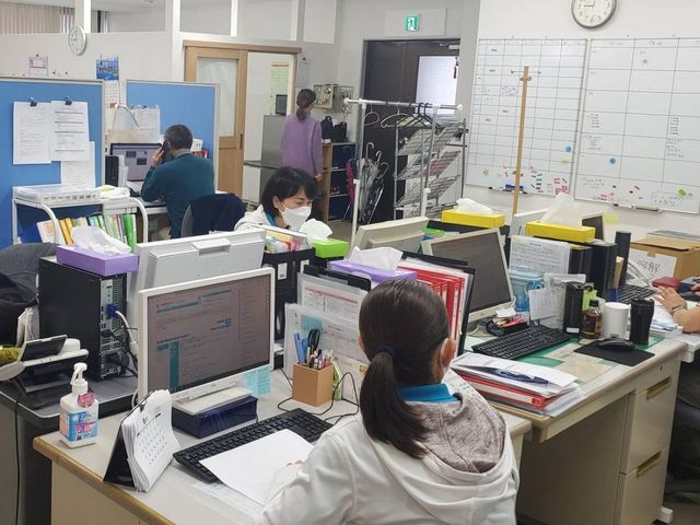 多忙なスタッフの執務室 スタッフイメージ 賑やかなオフィススペースで、職員が一体となって業務に取り組んでいます。やりがいを感じられる環境です。