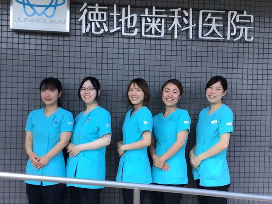 笑顔のスタッフが並ぶ外壁前  