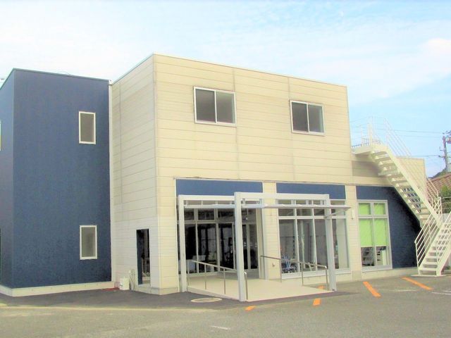施設の外観 外観   白と紺の外壁が印象的な2階建てです。正面に屋根付きの出入口があり、外階段も見えます。