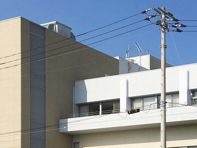 施設外観 外観   青空の下に整った外観が見え、白とベージュの落ち着いた配色です。窓やバルコニーが並び、明るく開放感があります。
