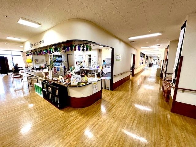 明るい廊下 廊下 広い廊下には自然光が差し込み、快適に移動できる空間です。奥にはスタッフがいます。