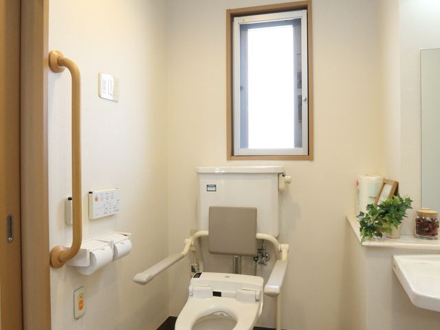 バリアフリー設計のトイレ トイレ 手すり付きの清潔感に溢れるトイレは、安全で快適な利用が想定されます。快適な職場環境を目指している方に適しています。
