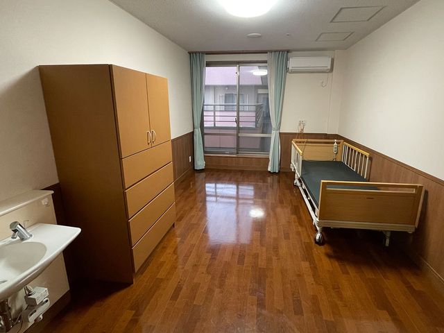 落ち着いた個室の居室 居室 広々としたスペースで、ベッド近くには十分な収納があります。快適な生活をサポートします。