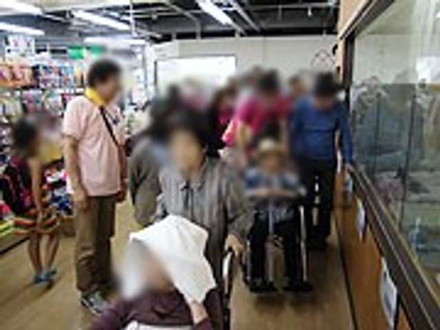 商品が並ぶ売り場 ショップ 明るい売り場で、車椅子でも快適に買い物が楽しめます。多数の人々が利用しています。