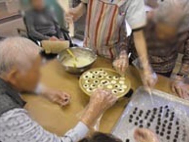 お菓子作り風景 ダイニングルーム 利用者が集まり、楽しくお菓子作りをしています。交流を深める温かな時間が流れています。