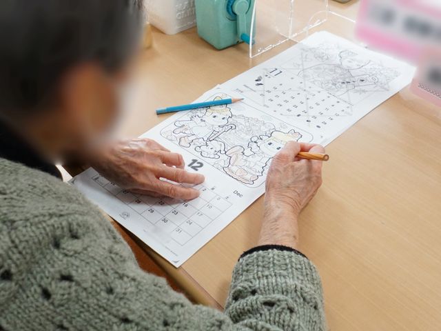 多目的スペースで憩う人 レクリエーション ゆったりとした時間の中で、色鉛筆を使って絵を描く楽しみを提供しています。お一人おひとりの趣味や興味を大切にした穏やかな環境です。