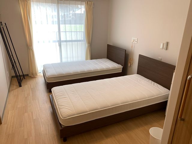 穏やかな雰囲気の居室 居室   明るい自然光が差し込む居室です。ベッドが整然と配置され、リラックスできる空間になっています。
