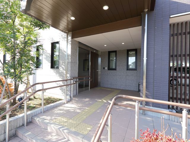 明るく清潔なエントランス 玄関 手すり付きの坂道が整備されたエントランスです。安全に配慮された設計で、働く環境も整っています。