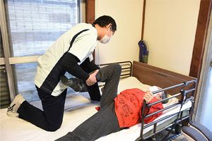 介護者の支援で体操する様子