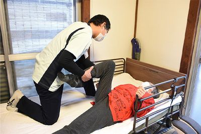 介護者の支援で体操する様子