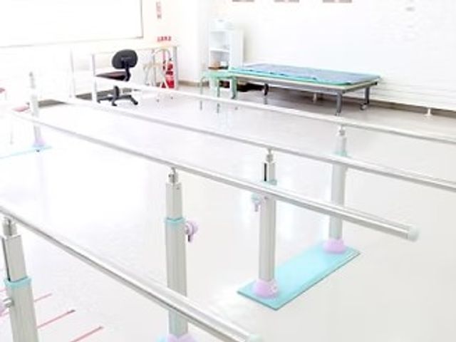 機能訓練室の手すり 機能訓練室   白を基調にした明るい空間に、歩行練習用の手すりが整っています。奥には訓練用ベッドも見え、落ち着いて体を動かしやすそうです。
