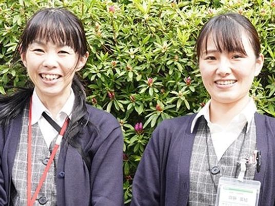 笑顔のスタッフ2人と植え込みの前  