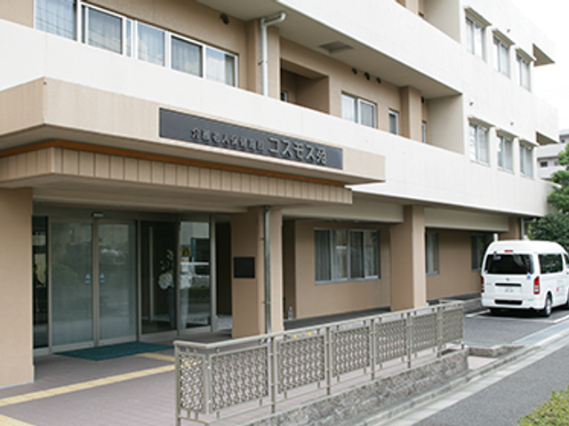 白い送迎車と建物の外観 外観 車椅子でも快適に利用できる、広めのエントランスと送迎サービスが整っています。