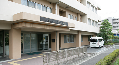 白い送迎車と建物の外観