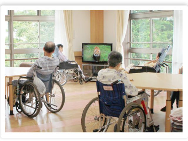 テレビを観る風景 リビング 広々とした明るい空間では、車椅子の人々がテレビを見ながらリラックスしています。