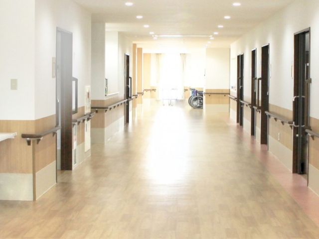 長い廊下 廊下 広々とした廊下は、手すりがあり安全に移動できます。奥には車椅子も見え、使いやすさが整っています。