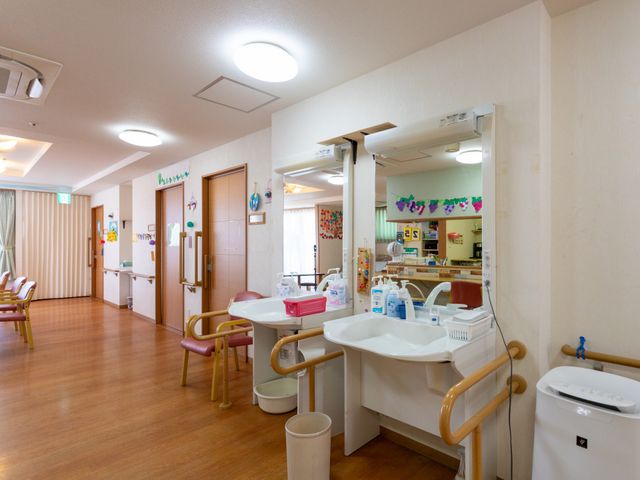 笑顔のスタッフと入居者 ケア 笑顔あふれる応接スペースで、心温まる対話が交わされています。