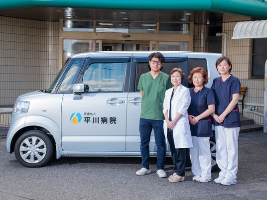 送迎車の前の職員  