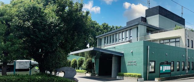 緑の建物の正面玄関 外観 緑が豊かな環境に囲まれた建物です。明るい外観が働く環境の良さを感じさせます。