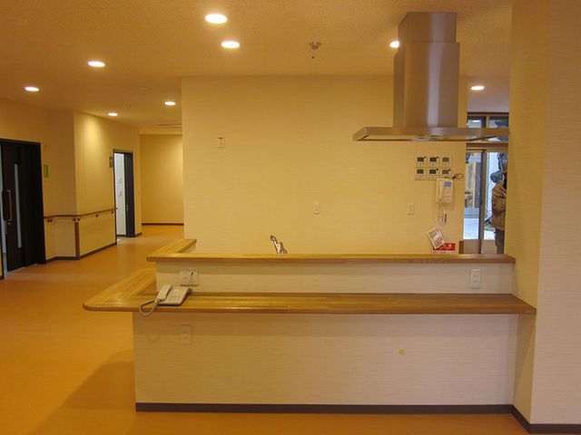 手話通訳所 フロント 温かみのある色合いの受付カウンターで、スタッフの方が丁寧に対応しています。ゆったりとした空間設計で、ご来訪の際に安心感を得られる場所です。