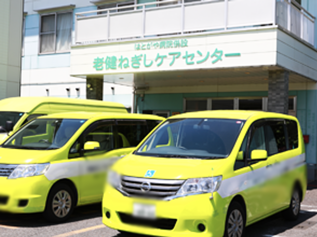 緑色の車両と建物の外観 外観 アクセスが便利な立地にある施設の外観です。外出支援用の車両が用意されています。