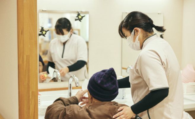 洗面を手伝うスタッフの姿