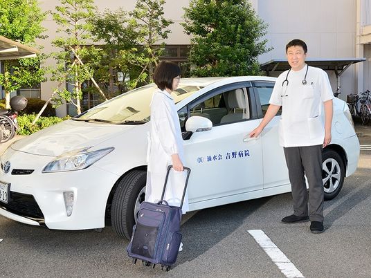 送迎車の前に立つスタッフ  